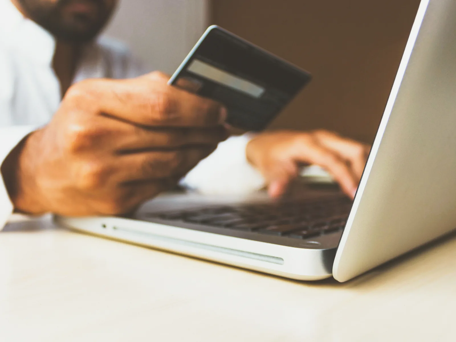 Una mano con una carta di credito davanti a un portatile
